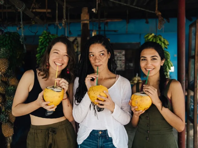 three girls drinking king coconut in a local stall