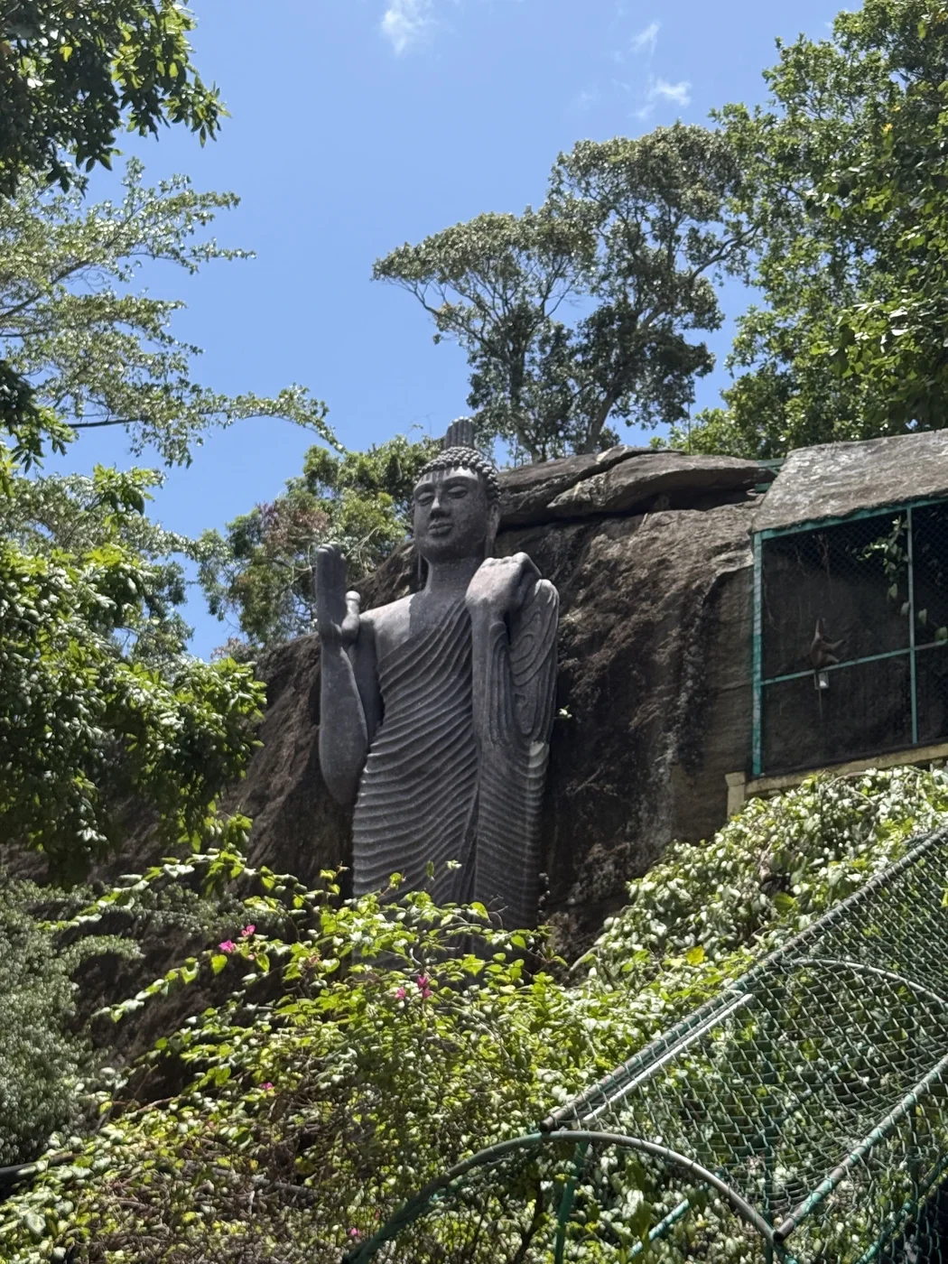 Standing Buddha statue beside a rock