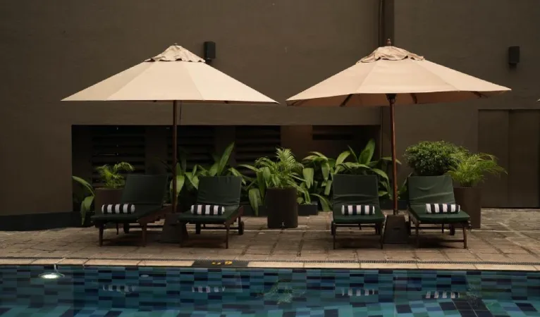 Pool with sun loungers under white umbrellas at Hotel Casamara Kandy