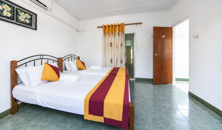 Twin room with maroon and yellow bed runners at Charlton Kandy Rest
