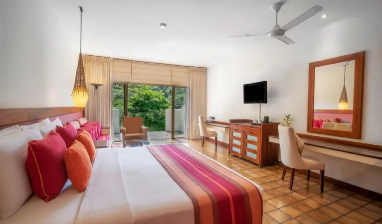 Guest room with striped bed runner and red cushions at Cinnamon Citadel Kandy