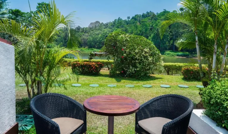Two wicker chairs on a riverside lawn at Cinnamon Citadel Kandy