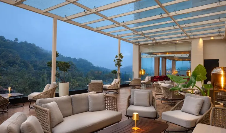 Glass-roofed terrace lounge with sofas overlooking misty hills at The Golden Crown Hotel
