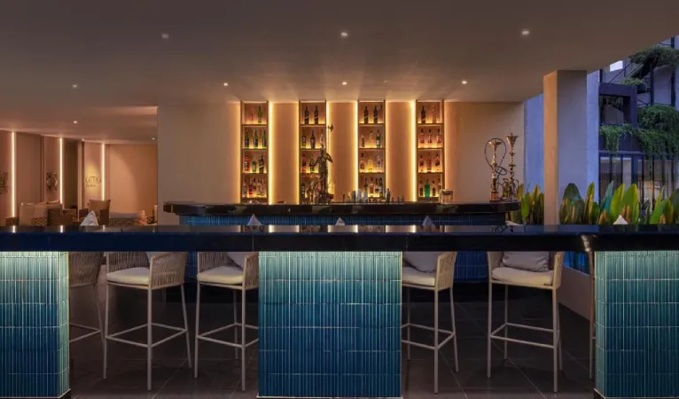 Bar with backlit bottle shelves and teal-tiled counter at The Golden Crown Hotel