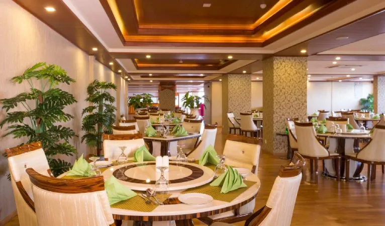 Restaurant with round tables and folded green napkins at The Grand Kandyan Hotel