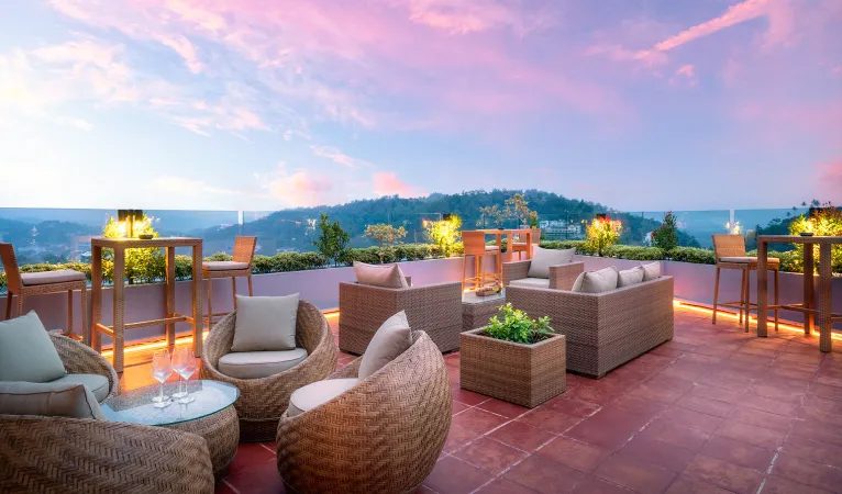 Rooftop lounge terrace with wicker chairs at sunset, Grand Serendib Hotel Kandy