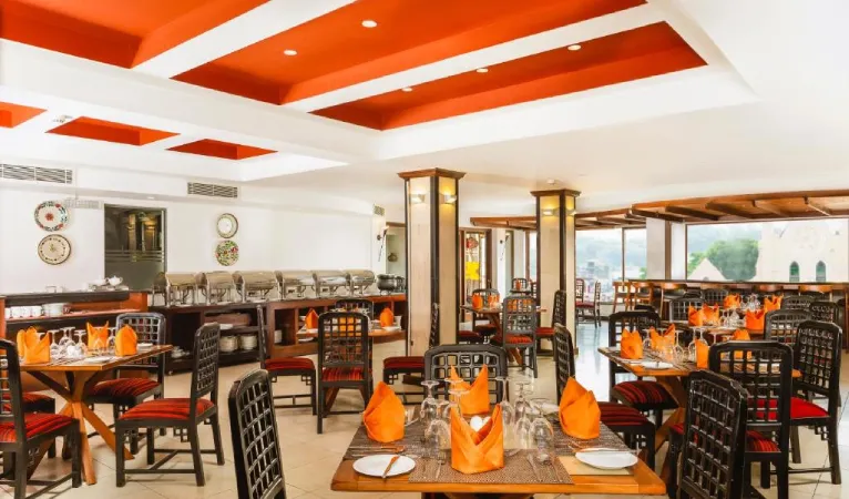 Restaurant with orange ceiling and set tables at Kandy City Hotel by Earl's