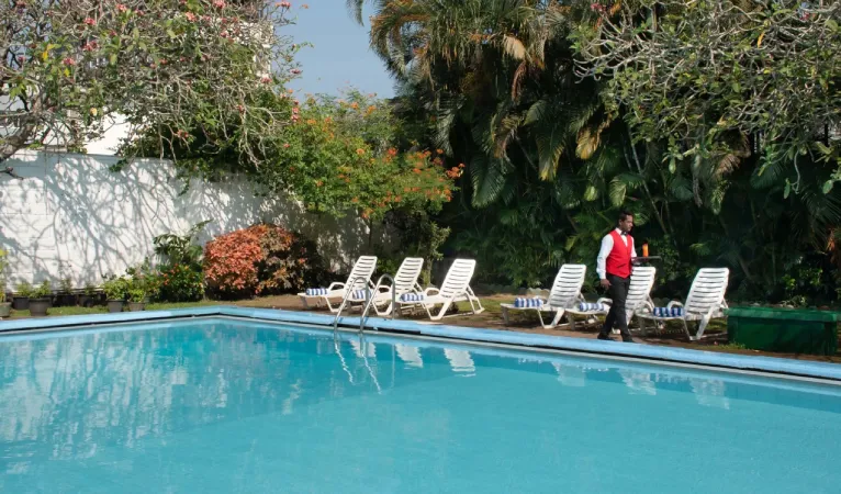 Swimming pool with white sun loungers in the garden of Queens Hotel Kandy