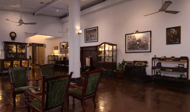 Colonial lounge at Queens Hotel Kandy with green armchairs and antique wooden cabinets
