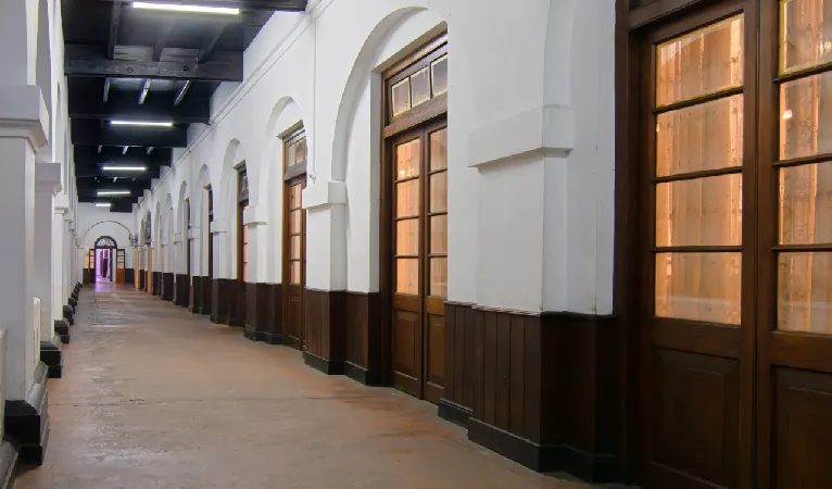 Long arched corridor with dark wooden doors inside Queens Hotel Kandy