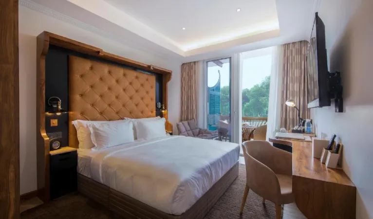 Guest room with a tall tufted headboard and writing desk at The Radh Hotel Kandy
