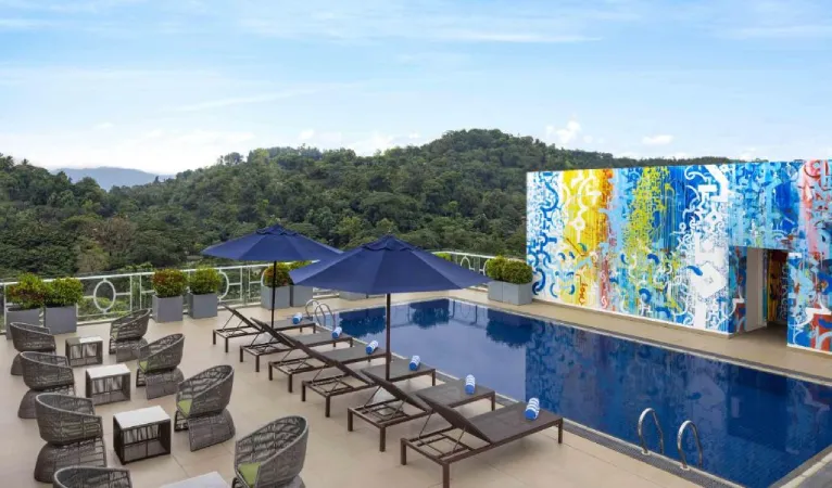 Rooftop pool with sun loungers and a colourful mural wall above Kandy's forested hills, Radisson Hotel