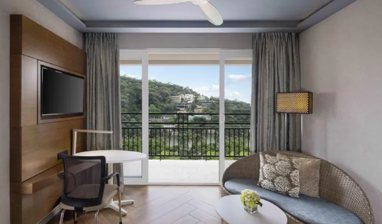 Room seating area opening onto a balcony with hill views at Radisson Hotel Kandy