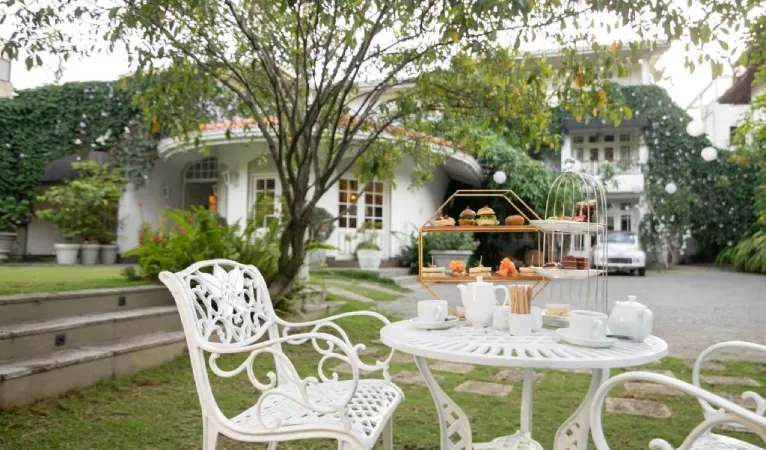 Afternoon tea on a white garden table in front of Ru Boutique's colonial house