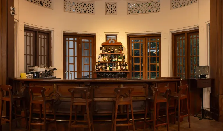 Wooden bar counter and stools in a round colonial room at Hotel Suisse Kandy