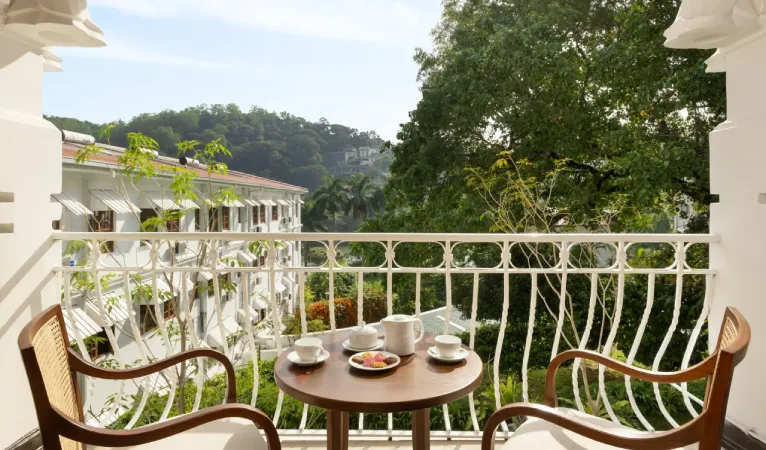 Balcony with tea for two and a wrought-iron railing overlooking trees at Hotel Suisse