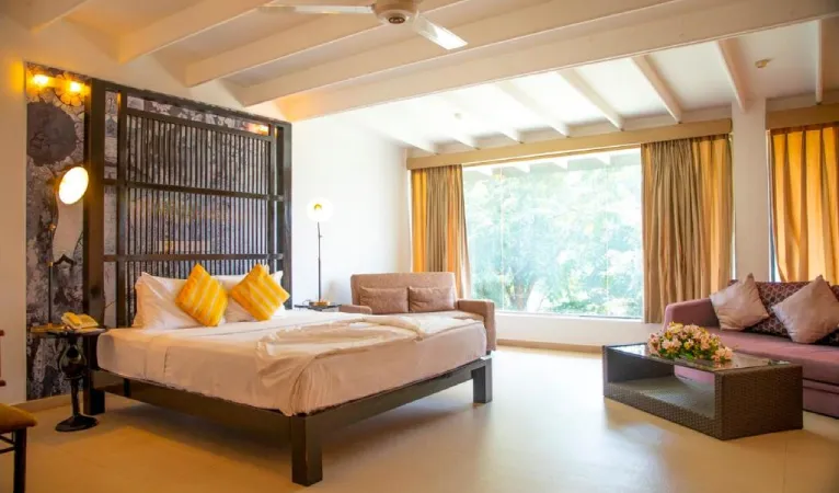 Guest room with yellow cushions, a sofa and garden-view windows at Thilanka Hotel Kandy