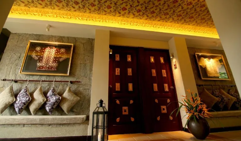 Seating nook with framed traditional garments and carved doors at Thilanka Hotel