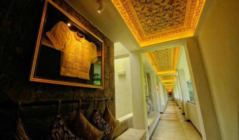 Long corridor with framed textiles and an ornate ceiling at Thilanka Hotel Kandy
