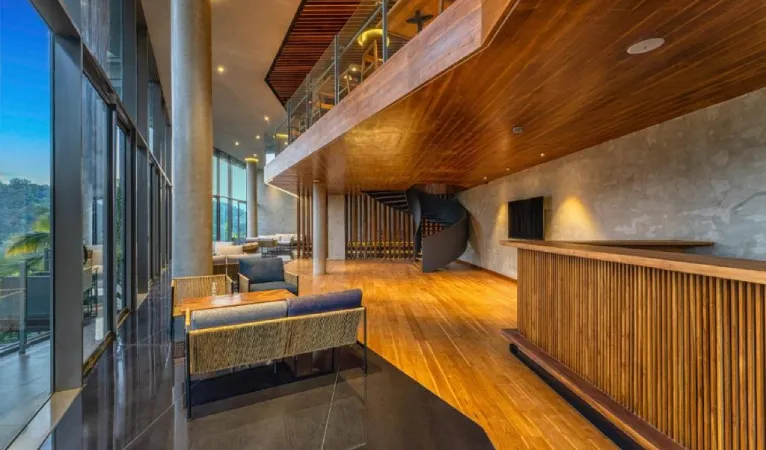 Double-height lounge with timber ceiling and glass walls at The Trees Kandy