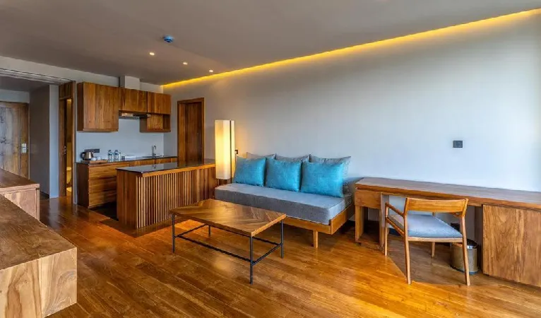 Suite living area with blue-cushioned sofa and kitchenette at The Trees Kandy