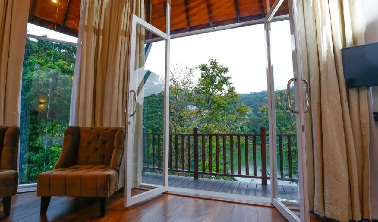 Open doors to a wooden balcony overlooking trees at Viyana Boutique Hotel Kandy
