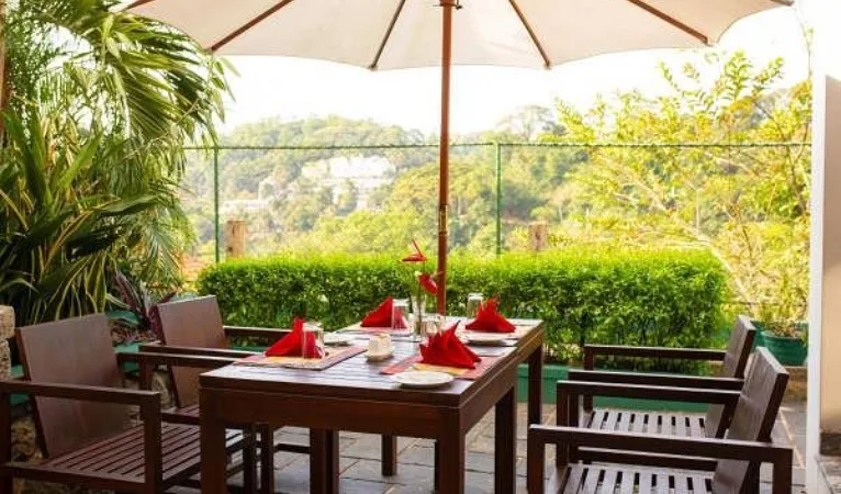Outdoor dining terrace with red napkins and hill views at Hotel Yo Kandy